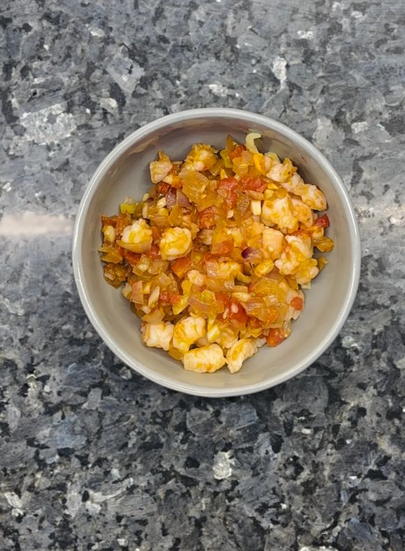 Stir in the cooked onion, tomato, and shrimp mixture before transferring everything to an oven-proof baking dish