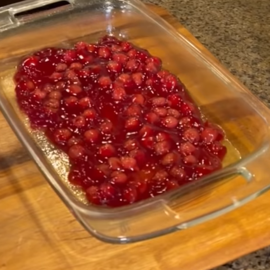 This image shows the process of cherry dump cake where cherry filing is filled in container.