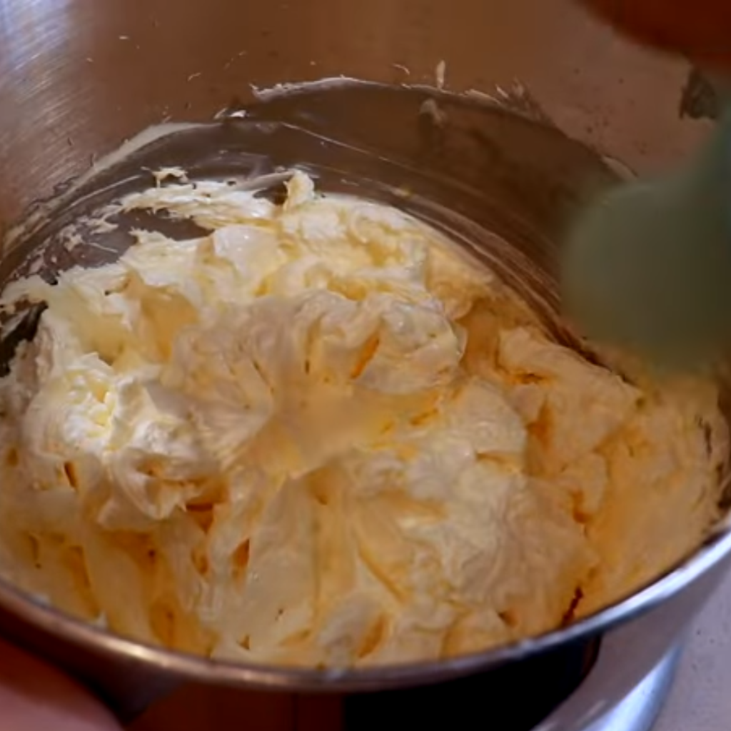 The image shows the mixture of sugar syrup, butter and egg yolks for french buttercream recipe