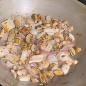 The image shows the process of cooking seafood medley in a skillet