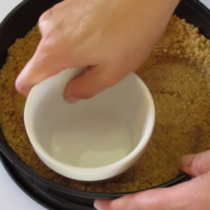 This image shows graham cracker crumbs pressed in a pan