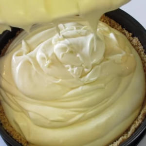 This image shows adding batter for cheesecake to the graham cracker crumbs