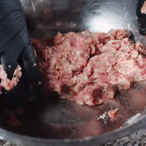 The image shows the process of adding pork to the mixture for irish sausage rolls