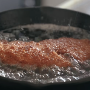 This image shows fryig chicken katsu in oil