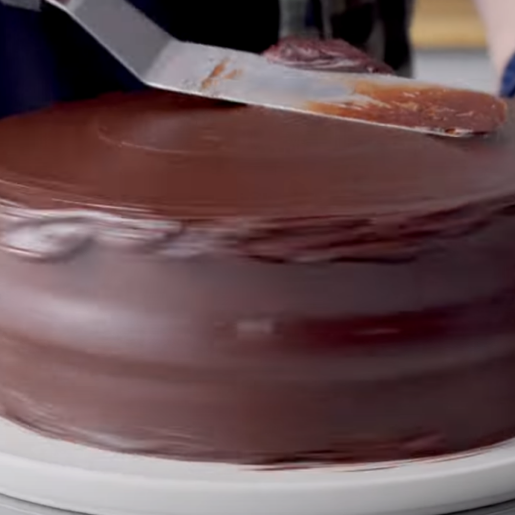 This image shows spreading frosting over the cooled cake.