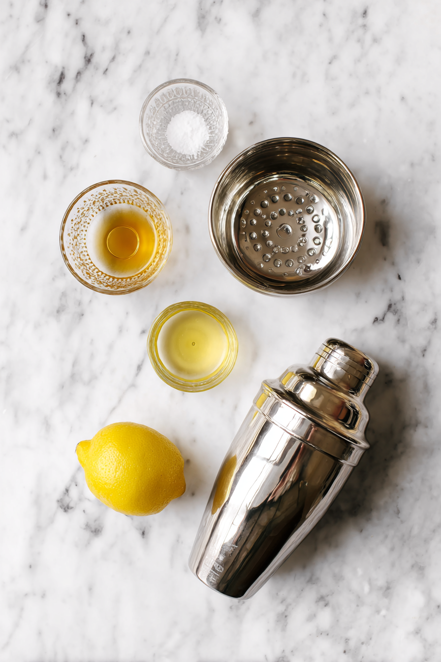 Make Cocktail: Fill a cocktail shaker with ice. Pour in honey syrup, freshly squeezed lemon juice, and gin.