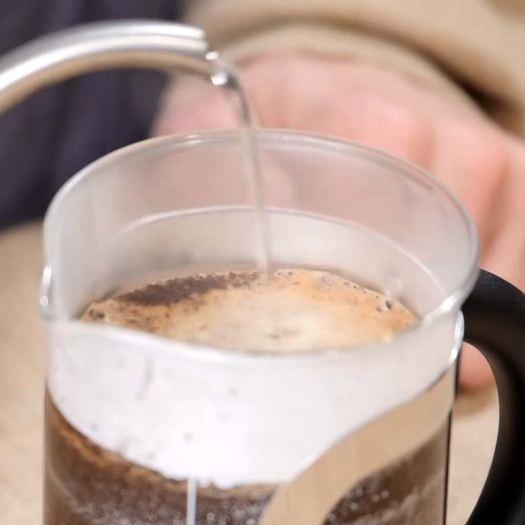 This image shows pouring boiled water into french press coffeee maker with bcoffee for french pres coffee