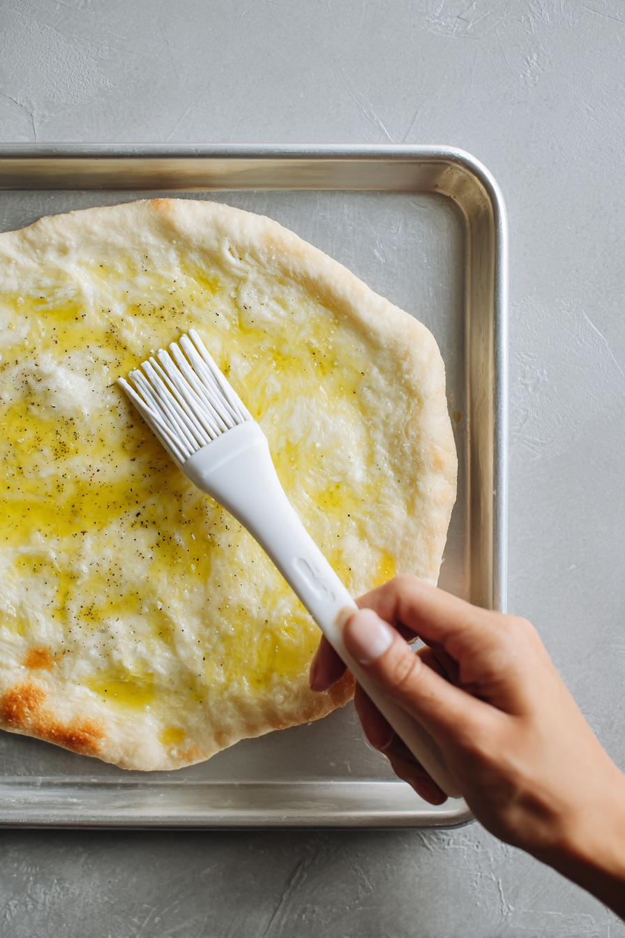 Spread the pizza crust into the pan, stretching it to the edges. Brush with olive oil and poke with a fork.