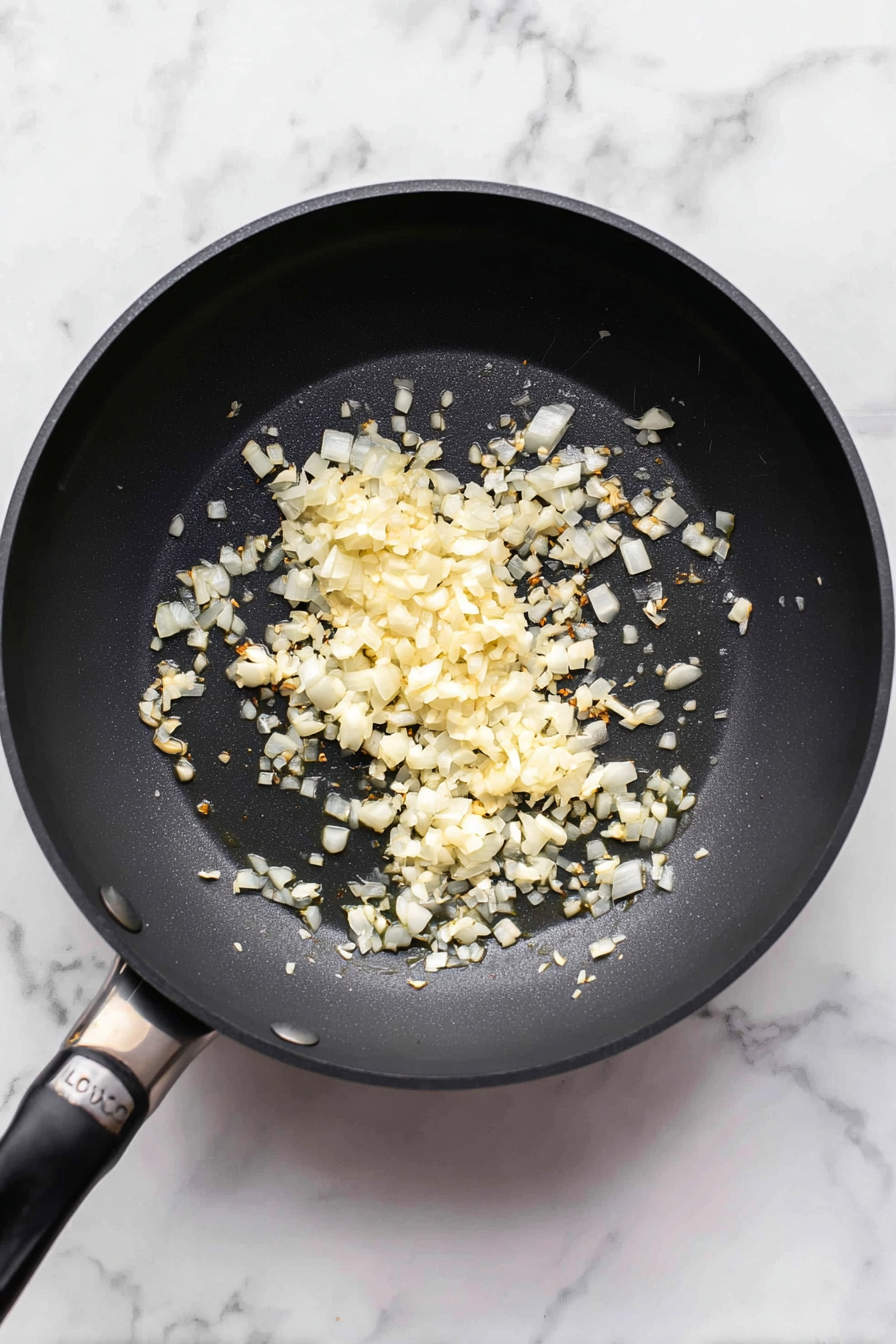 Reduce heat to medium-low, add remaining olive oil, garlic, and onion. Sauté for 2 minutes.