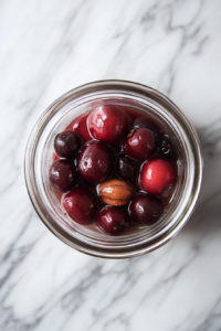 Strained cherry-infused liquid standing in a bowl on a marble countertop overnight, with sediment gradually settling at the bottom.