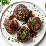 This image shows a perfectly cooked filet mignon steak covered in a rich marsala wine sauce and surrounded by sautéed mushrooms, creating a stunning presentation for the steak marsala recipe.