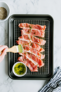 the image shows prepare the pork strips skin-side up on a baking rack set inside a baking sheet