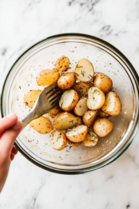 the image shows toss the potatoes into olive oil, garlic powder and so on