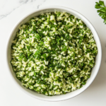 A serving of vibrant Chimichurri rice garnished with fresh parsley and cilantro in a bowl, ready to be served as a side dish.