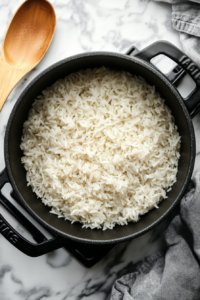 White rice simmering in water inside a medium pot on the stovetop as part of the Chimichurri Rice recipe preparation.