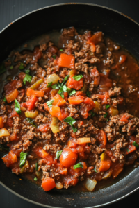 A pot of rich bolognese sauce with ground meat, vegetables, and tomatoes simmering gently, thickening and melding flavors for the linguine bolognese.