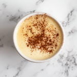 A close-up of a serving of Cuban Natilla, showing the smooth, velvety texture of the cinnamon and vanilla-flavored custard in individual bowls.