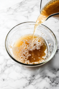 Image Name: Whisking Chickpea Stir-Fry Sauce as It Thickens Alt Text: A close-up of a whisk stirring the bubbling sauce as it thickens on the stove, preparing for the addition of chickpeas in this savory chickpea stir-fry recipe.