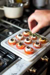 Adding olive slices to create eyes for the cream cheese stuffed tomato eyeballs