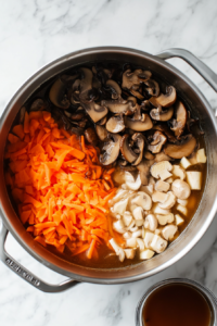 Adding tamari, broth, garlic, ginger, carrot, and dumplings to the Dumpling Soup recipe