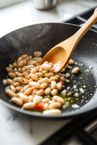 Beans, lemon juice, and seasonings being mixed into infused oil