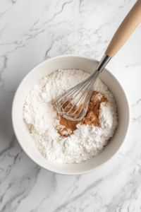 Mixing Dry Ingredients for Apple Cider Doughnuts in a Large Bowl