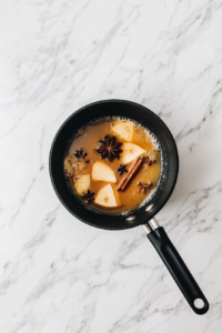 Non-Alcoholic Spiced Apple Fizz Recipe Heating Apple Juice with Cinnamon and Cloves in a Saucepan