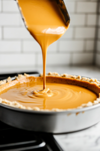 Pouring pumpkin cheesecake filling onto the baked crust