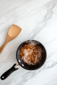 Spiced apple juice mixture with orange zest, cinnamon stick, and cloves simmering gently in a saucepan for 5 minutes, releasing aromatic flavors.