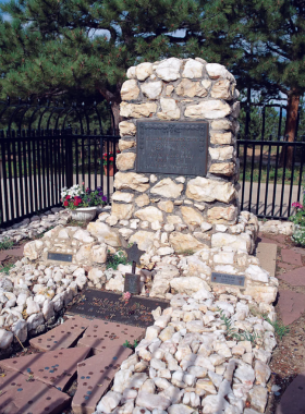 A detailed image of a grave marker featuring a statue, surrounded by lush greenery. The serene atmosphere evokes a sense of remembrance and tranquility, highlighting the artistry of the monument in a peaceful setting.