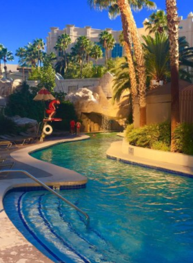 Sandy beach and pool area at Mandalay Bay Resort in Las Vegas, featuring palm trees, crystal-clear water, and a relaxing tropical ambiance for guests.