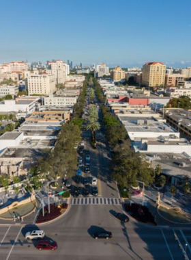 Aerial view of Miracle Mile in Coral Gables, showcasing vibrant streets lined with shops and trees under a clear blue sky.