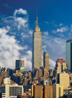 Towering view of the Empire State Building amidst Midtown Manhattan’s skyline, a landmark representing New York City’s architectural legacy.