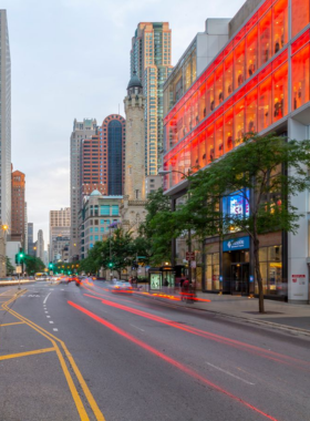  An expansive view of the Chicago skyline at dusk, with skyscrapers silhouetted against a colorful sunset sky. The image captures the dynamic energy of the city as lights begin to twinkle in the buildings, reflecting the vibrant nightlife. This photograph showcases Chicago's architectural diversity and urban charm.