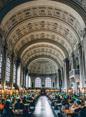 Bates Hall, a grand reading room at the Boston Public Library with high arched ceilings, large windows, and rows of green reading lamps. This elegant room is a quiet sanctuary for readers and visitors in Boston.