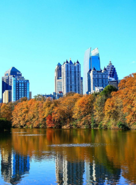 A scenic view of Piedmont Park in Atlanta, with open green fields, a tranquil lake, and a backdrop of the city skyline, offering a relaxing outdoor space for recreation and events.