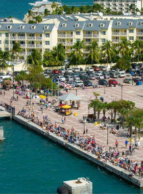 his image shows Mallory Square at sunset in Key West, with crowds gathering to watch the sun dip below the horizon. The scene captures the lively atmosphere of street performances and beautiful coastal views.