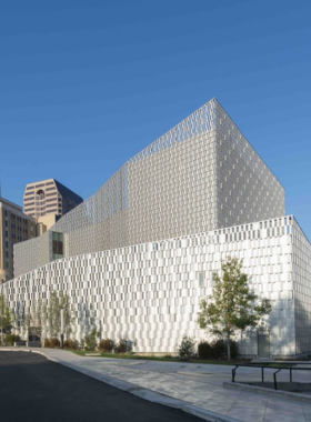  A modern bridge structure framed by contemporary buildings, set against a soft sky. The architectural design highlights urban sophistication and connectivity.