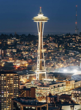  The famous Space Needle, standing tall against a bright blue sky, with the surrounding cityscape below. The landmark symbolizes Seattle’s skyline and modern architectural style.

