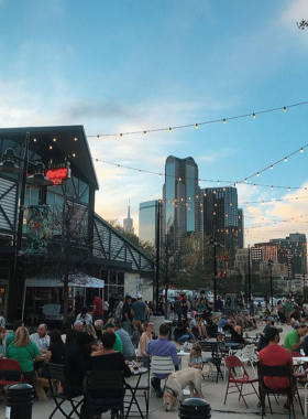 A lively celebration at the Dallas Farmers Market during St. Patrick's Day, with people dressed in festive green attire and market booths around."