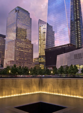 A serene view of the 9/11 Memorial, featuring the reflecting pools and surrounding trees, honoring the victims of the tragedy.