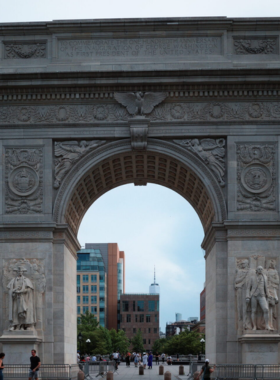 An aerial view of Washington Square Park, featuring its iconic arch, green spaces, and people enjoying leisure activities.

