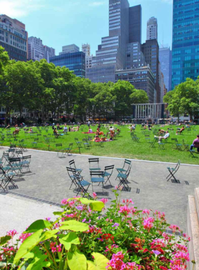 A scenic view of Bryant Park in New York City, featuring green lawns, surrounding skyscrapers, and visitors enjoying the open space.