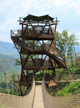 A majestic portrait of Gatlinburg Tower, showcasing its impressive structure against a clear blue sky. The tower is surrounded by greenery, embodying the scenic beauty of the Smoky Mountains.