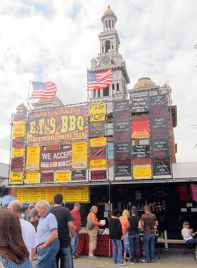  A lively outdoor scene from the Bloomin' BBQ Festival in Gatlinburg, featuring colorful tents and visitors enjoying various barbecue dishes. The event is filled with music and laughter, showcasing the festive spirit of the local community.