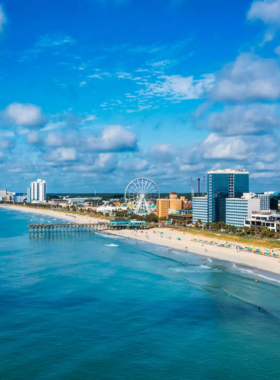  A scenic view of Myrtle Beach's promenade, showing the beautiful shoreline with clear blue waters and tourists enjoying the sun and sand. The beach offers a relaxed atmosphere with plenty of activities.