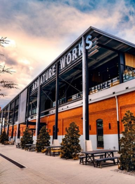 A vibrant food hall at Armature Works, showcasing a variety of delicious foods and beverages from local vendors, with guests enjoying meals and drinks while overlooking the Hillsborough River.