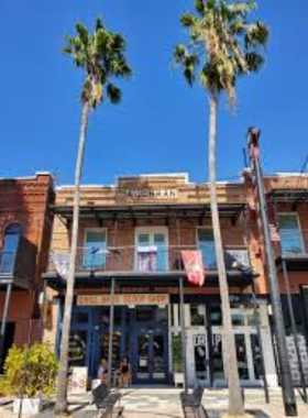 A view of the charming, historic brick buildings in Ybor City, lined with shops and restaurants, with people walking along the cobblestone streets enjoying the lively atmosphere.