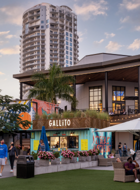 Guests dining outdoors at Sparkman Wharf, enjoying fresh food and craft beer with a scenic view of the waterfront and modern architecture surrounding the space.