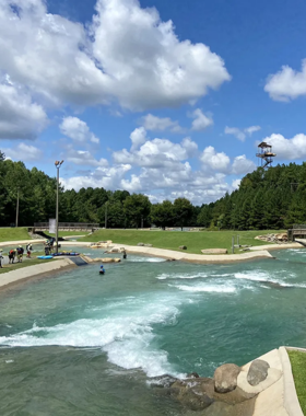 This image shows that visitors are participating in an exciting whitewater rafting experience at the U.S. National Whitewater Center, navigating through fast-moving water with kayaks and rafts.